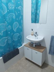 a bathroom with a sink and a blue shower curtain at Puerto Pesquero de Cariño in Cariño