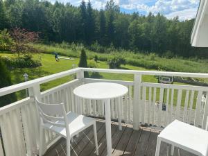 a white table and chairs on a deck with a view of a field at Big house with jacuzzi by the forrest in Hudiksvall
