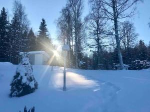 a snow covered yard with the sun shining through the trees at Big house with jacuzzi by the forrest in Hudiksvall