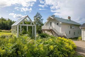 una casa blanca con un invernadero en un jardín en Big house with jacuzzi by the forrest en Hudiksvall