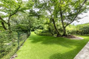 a green yard with trees and a fence at Hanare no Yado Hanagokoro in Minamioguni