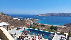 a group of people standing around a swimming pool at Villas Kappas in Agios Sostis Mykonos
