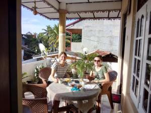 twee vrouwen aan een tafel op een balkon bij Randi Homestay in Negombo