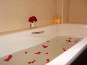 a white bath tub with red flowers and a vase of roses at Apartamentos en sierra de gata la Noguera 2 in Villamiel