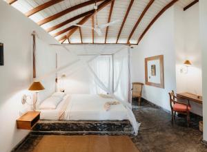 a bedroom with a white bed and a desk at Amuura Beach Villa in Beruwala