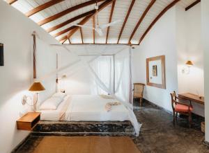 - une chambre avec un lit blanc et un bureau dans l'établissement Amuura Beach Villa, à Beruwala