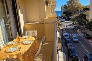 - une table sur un balcon avec vue sur la rue dans l'établissement Appart le Lavandou (le st James) 2 étoiles, au Lavandou