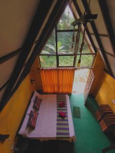 an attic room with a bed and a large window at Rainforest cabin in Deniyaya