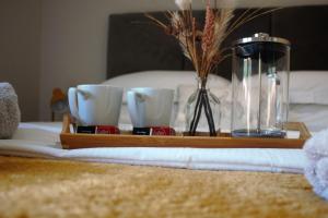 a tray with cups and a vase on a bed at The Squirrels- Alresford, Essex in Alresford