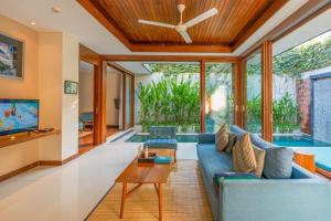 a living room with a blue couch and a tv at Maca Villas and Residence Umalas in Seminyak