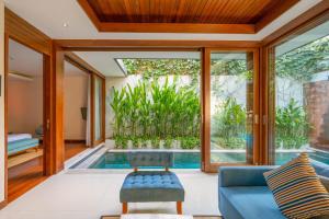 a living room with a pool and a blue couch at Maca Villas and Residence Umalas in Seminyak