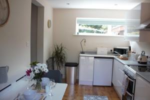 a kitchen with white appliances and a table with flowers on it at The Squirrels- Alresford, Essex in Alresford