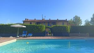 a house with a pool and two chairs and an umbrella at il Chiassetto Agriturismo No Kids in Cascina