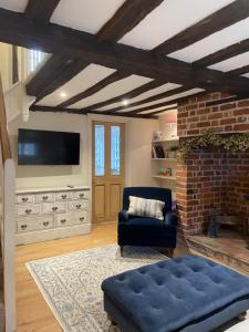 uma sala de estar com um sofá azul e uma televisão em Historic Cambridgeshire Cottage em Godmanchester