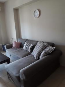 a living room with a couch and a clock on the wall at G3 sea view appartment in Igoumenitsa