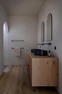 La salle de bains est pourvue d'un lavabo en bois et de deux miroirs. dans l'établissement fink Restaurant & Suites, à Brixen