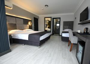 a hotel room with two beds and a desk and a television at Sahil Hotel Pendik in Tuzla