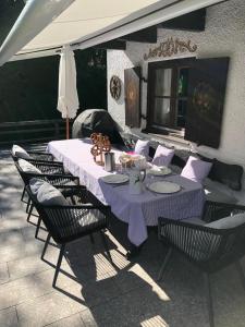 若特阿赫－埃根的住宿－Traumhaftes Ferienhaus direkt am Tegernsee，帐篷下配有紫色桌布和椅子的桌子