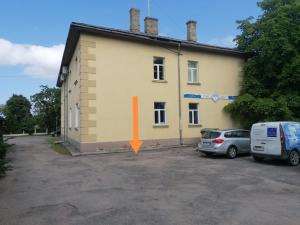 um edifício amarelo com uma seta laranja na lateral em Apartment Windau em Ventspils