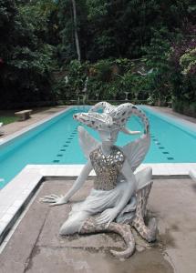 a statue of a mermaid sitting next to a swimming pool at HELGASFOLLY Anti Hotel Residence in Kandy