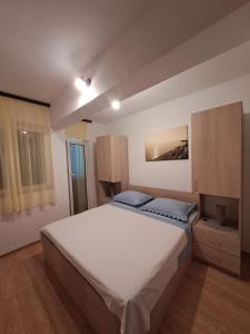 a bedroom with a large white bed and a window at Apartments Ostojic in Tučepi