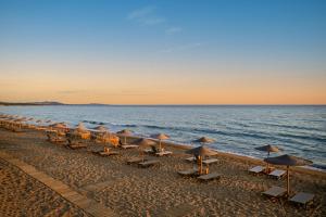 een rij parasols en stoelen op een strand bij KOUROUTA BEACH HOUSE in Kourouta