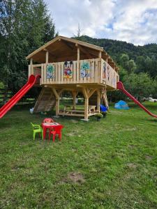 um parque infantil com uma casa de brincar com um escorrega em Căsuța dintre brazi em Rîşnov