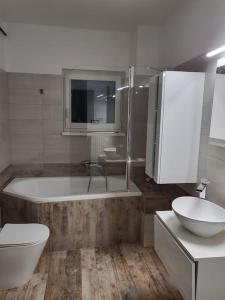 uma casa de banho com uma banheira, um WC e um lavatório. em Flower Apartman Győr em Gyor