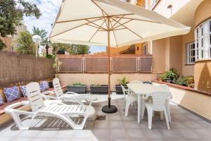 een patio met witte stoelen en een parasol bij La Casa Alegre in Alicante