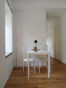 una mesa blanca con sillas y una lámpara. en Il monolocale, en Bosisio Parini