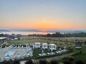 eine Gruppe von Tischen und Stühlen auf einem Feld mit Sonnenuntergang in der Unterkunft Family Hotel Eterno in Tsigov Chark