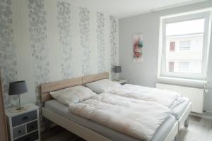 Schlafzimmer mit einem Bett mit weißer Bettwäsche und einem Fenster in der Unterkunft Appartementhaus Christel in Grömitz