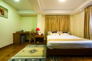 ein Hotelzimmer mit einem Bett, einem Schreibtisch und einem Schreibtisch in der Unterkunft Ambassador Hill in Yangon