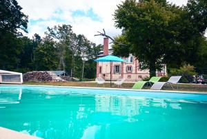 - une piscine avec des chaises et un parasol en face d'une maison dans l'établissement La Maison du Garde, domaine de La Drelas, 6 couchages, pierre et bois,, à Chaumont-sur-Tharonne