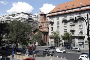 een drukke stadsstraat met auto's en gebouwen bij My Cozy Place in Boekarest
