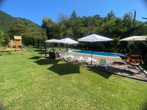 a swimming pool with chairs and umbrellas and a playground at CASA DRENCOVA SRL in Berzasca
