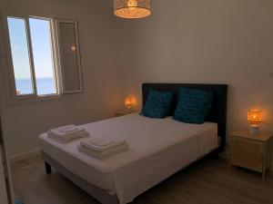a bedroom with a bed with blue pillows and a window at Magnifique maison avec vue mer hauteur de Bastia in Bastia