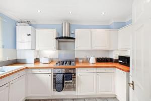 a kitchen with white cabinets and a stove top oven at Stunning Central London 2 Bed Parking & Garden in London