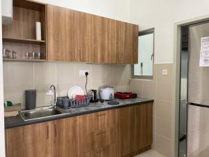 uma cozinha com armários de madeira e um lavatório em Alanis D'semporna Homestay em Sepang