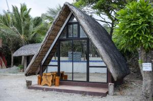 a small house with a thatched roof and a window at La Jose Beach Resort in Pagudpud