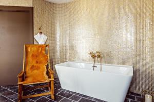 ein Bad mit einer weißen Badewanne in einer gefliesten Wand in der Unterkunft Grand Hotel Soleil d'Or in Megève
