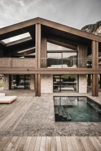 een huis met een zwembad op een houten terras bij Luxury Chalet Alpurio in Selva di Val Gardena