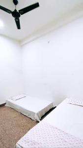 Cette chambre blanche dispose d'un lit et d'un ventilateur de plafond. dans l'établissement Dhanwantri Niwas, à Varanasi