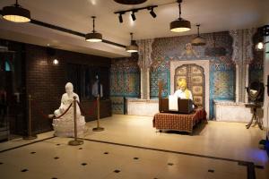 a room with two statues and a man sitting in a chair at Ambala Haveli in Ambāla