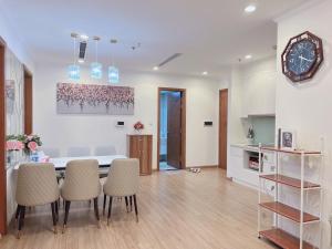 sala de estar con mesa, sillas y reloj en Vinhomes Time City and Parkhill Premium Apartment en Hanói