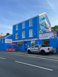 un camión estacionado frente a un edificio azul en See the Sea Hideaway, en Mumbles