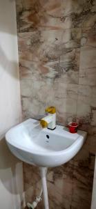 La salle de bains est pourvue d'un lavabo blanc et d'un mur en marbre. dans l'établissement Dhanwantri Niwas, à Varanasi