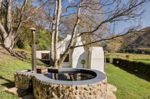 a stone fire pit in a yard with a tree at Somerset Gift Getaway Farm in Swellendam