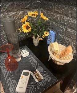 Vegan Inn Airport - Adults Only - SELF CHECK IN في فيوميتشينو: طاولة مع جهاز تحكم عن بعد و مزهرية مع الزهور