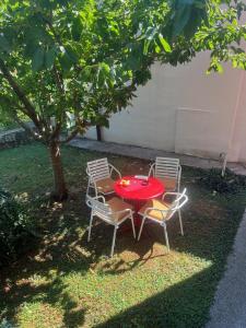 a table and two chairs with a red table and a tree at Gorica hill apartment in Podgorica